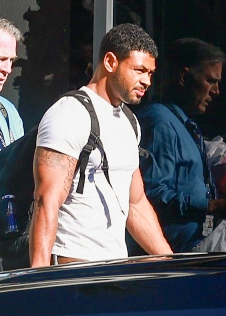 Mystery man with Britney Spears wearing a white t-shirt, black shorts, and a backpack.