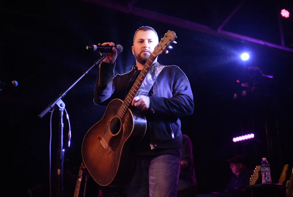Tyler Farr performs with a guitar and microphone.