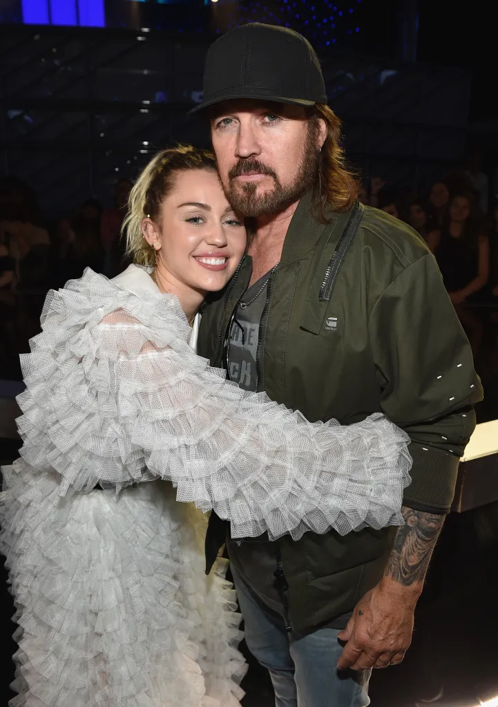 Miley Cyrus in a white dress hugging Billy Ray Cyrus at the 2017 Billboard Music Awards.