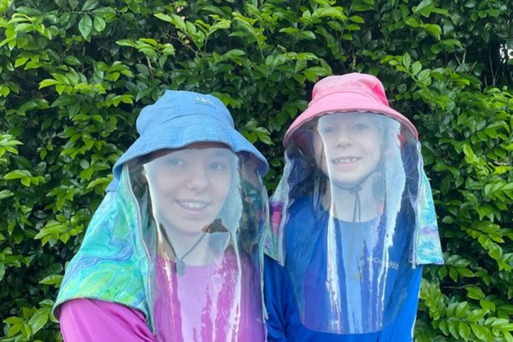 Sisters Amielle and Taya in sun-protective hats with face shields.