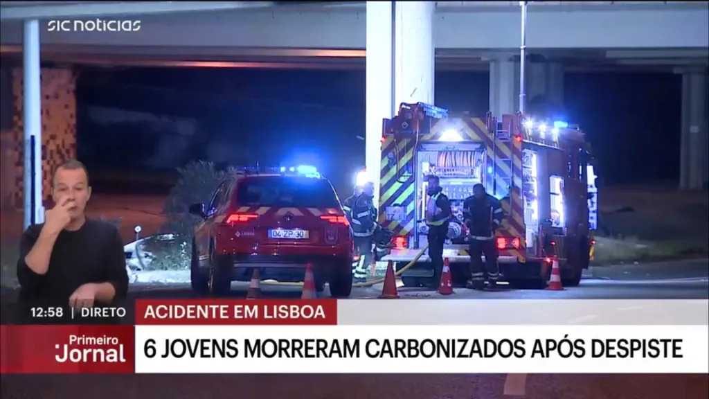 A news report showing a man speaking with a fire truck and emergency vehicles in the background at an accident scene in Lisbon where six young people died.