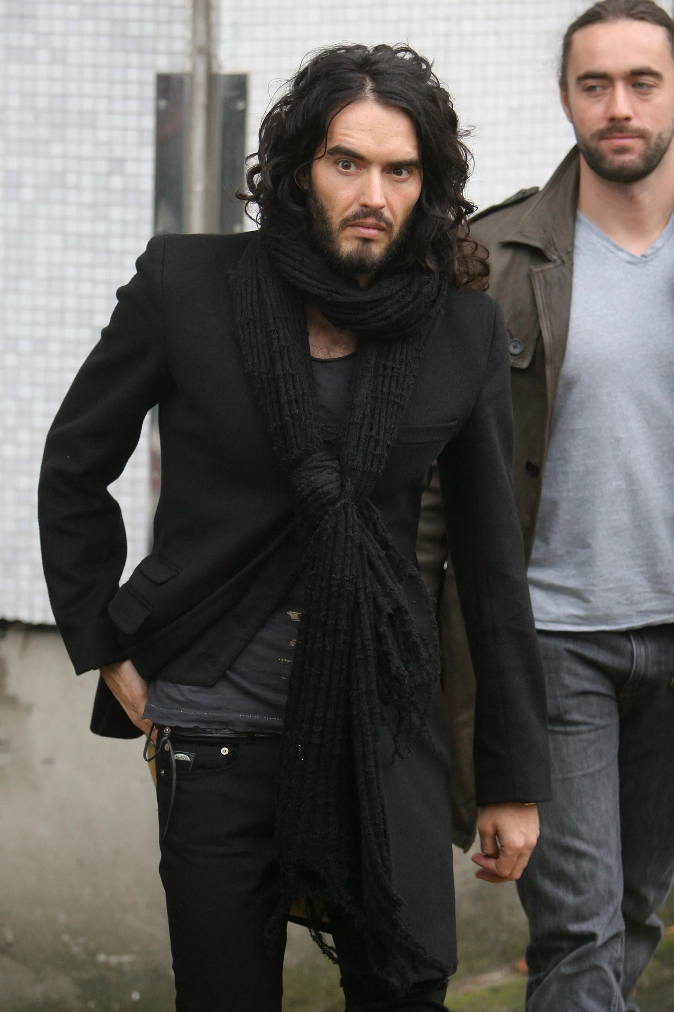 Russell Brand walking outdoors.