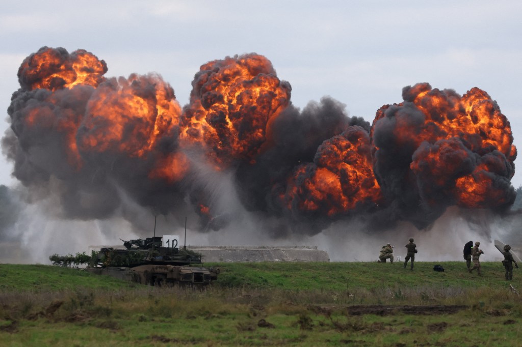 Smoke billowing from a blast near a Polish Abrams tank as Polish forces and NATO soldiers hold military exercises.