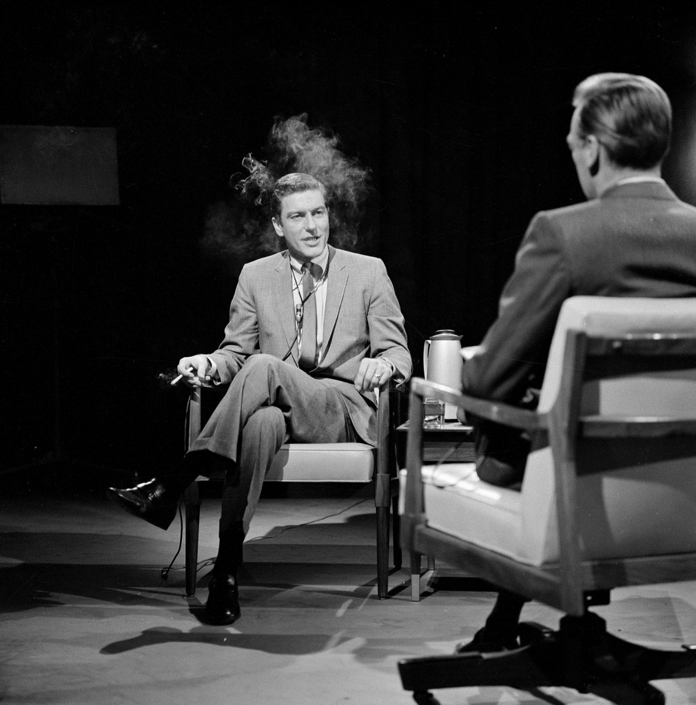 Rob Petrie smoking a cigarette while being interviewed by Ray Murdock.