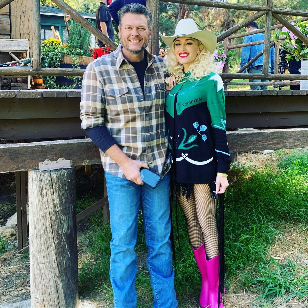 Blake Shelton and Gwen Stefani posing together, with Stefani wearing a cowboy hat and pink boots.