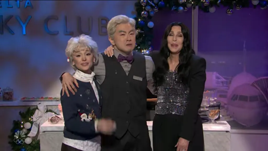 Cher and Bowen Yang with Ariana Grande as an elderly woman, posing for a photo.
