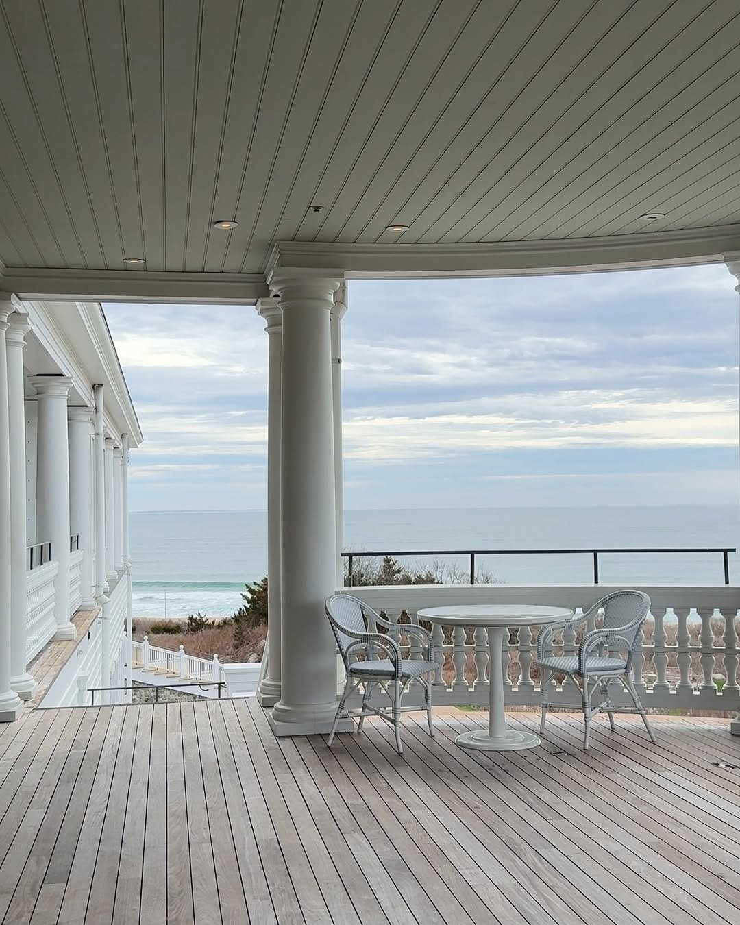 View of the Ocean House in Rhode Island from a porch with two chairs and a table.