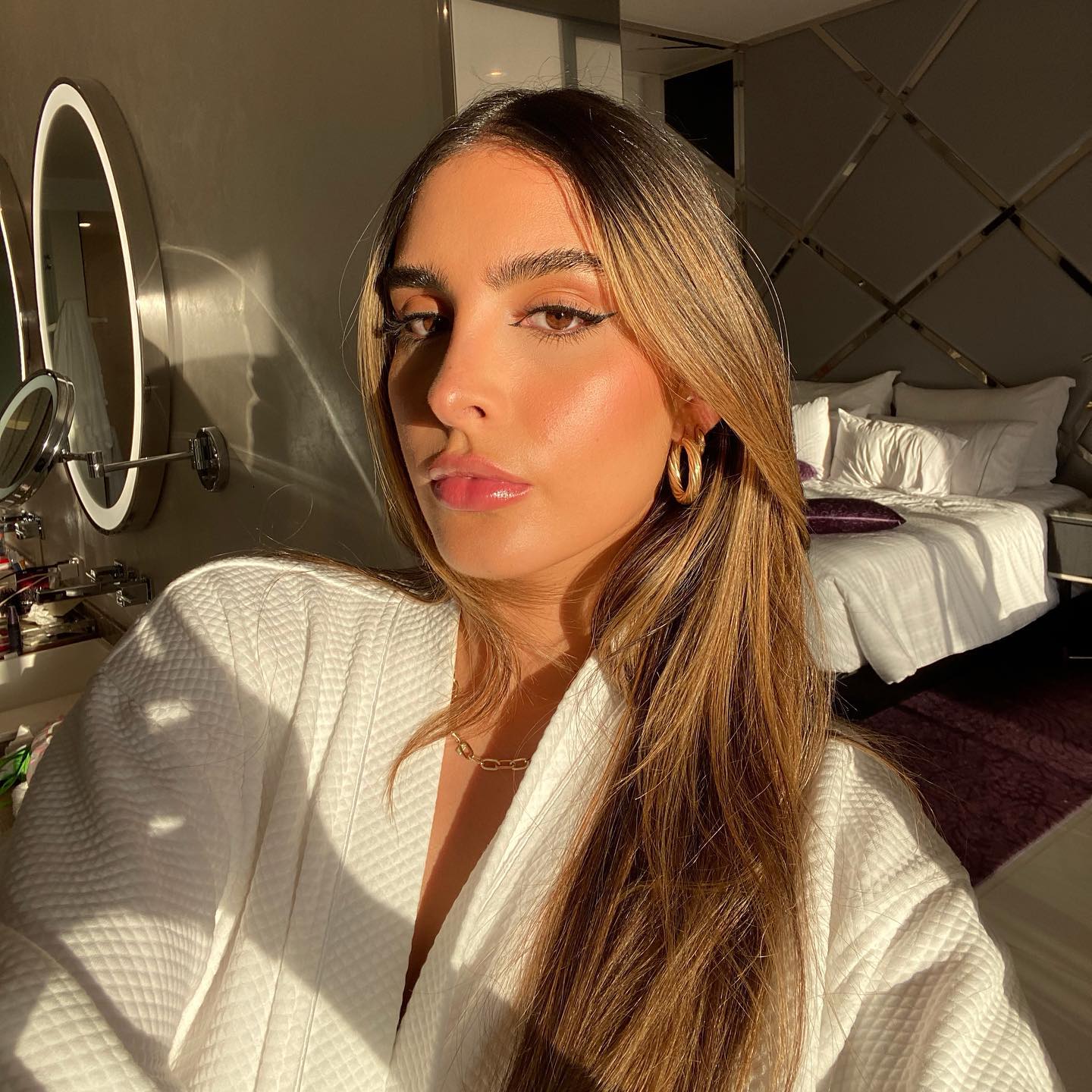 Sophia Kylie Umansky wearing a white robe and gold earrings.