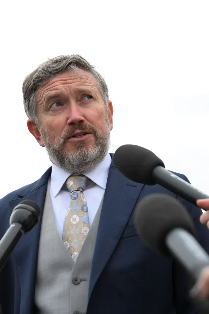 U.S. Representative Thomas Massie speaking to media, surrounded by microphones.