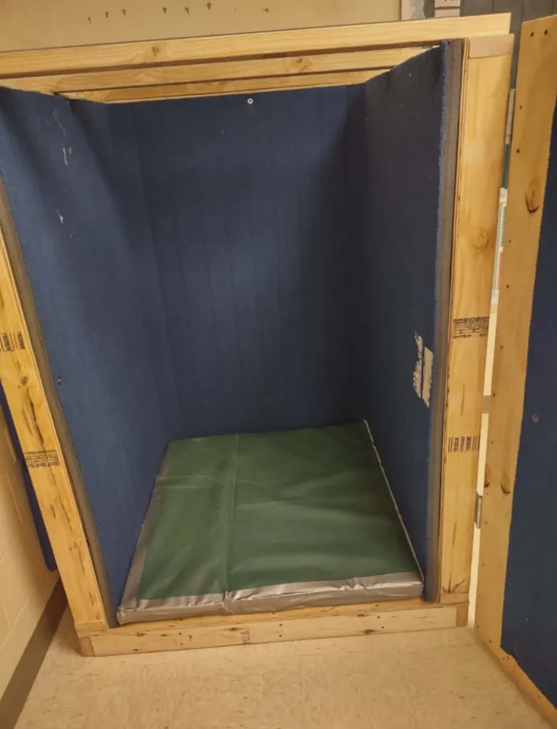 Wooden box lined with dark blue fabric and a green mat on the floor, used for 