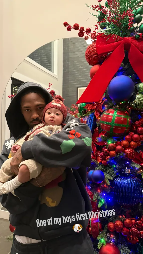 Stefon Diggs holding his infant child in front of a Christmas tree.
