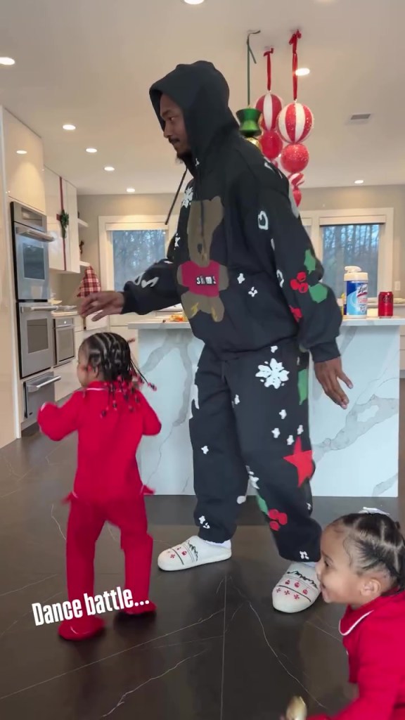 Stefon Diggs dancing with two of his children, who are both dressed in red outfits.