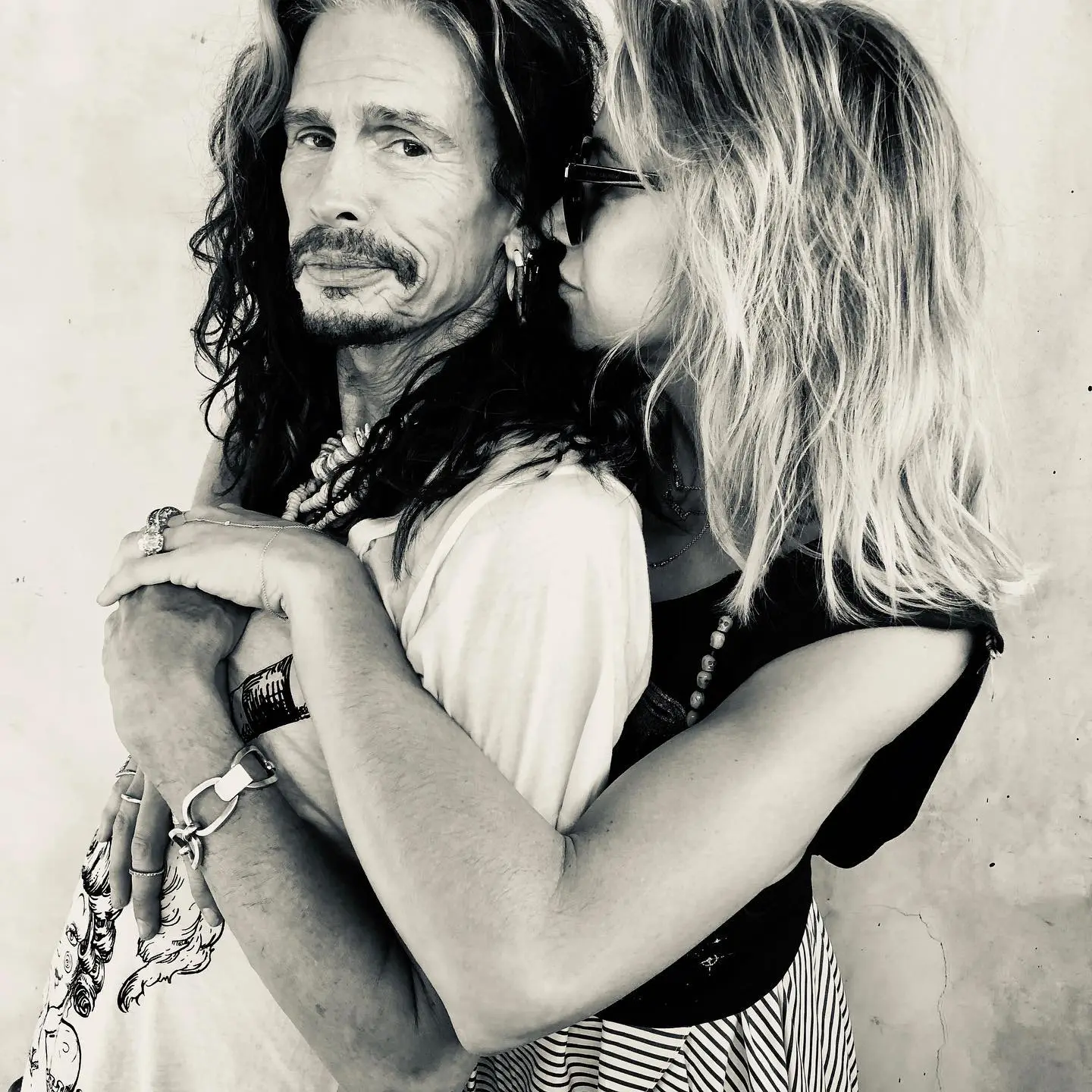 Steven Tyler and Aimee Preston embrace in black and white.