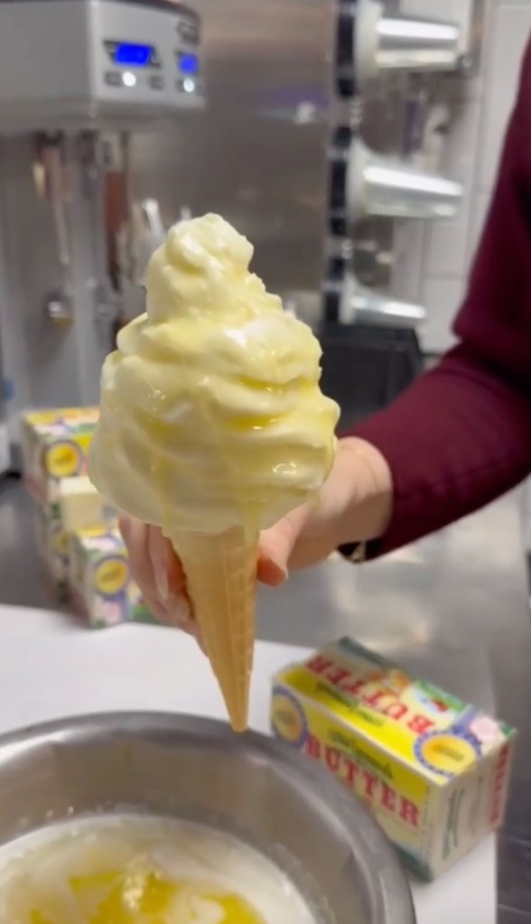A vanilla soft-serve ice cream cone being dipped into a bowl of melted butter.