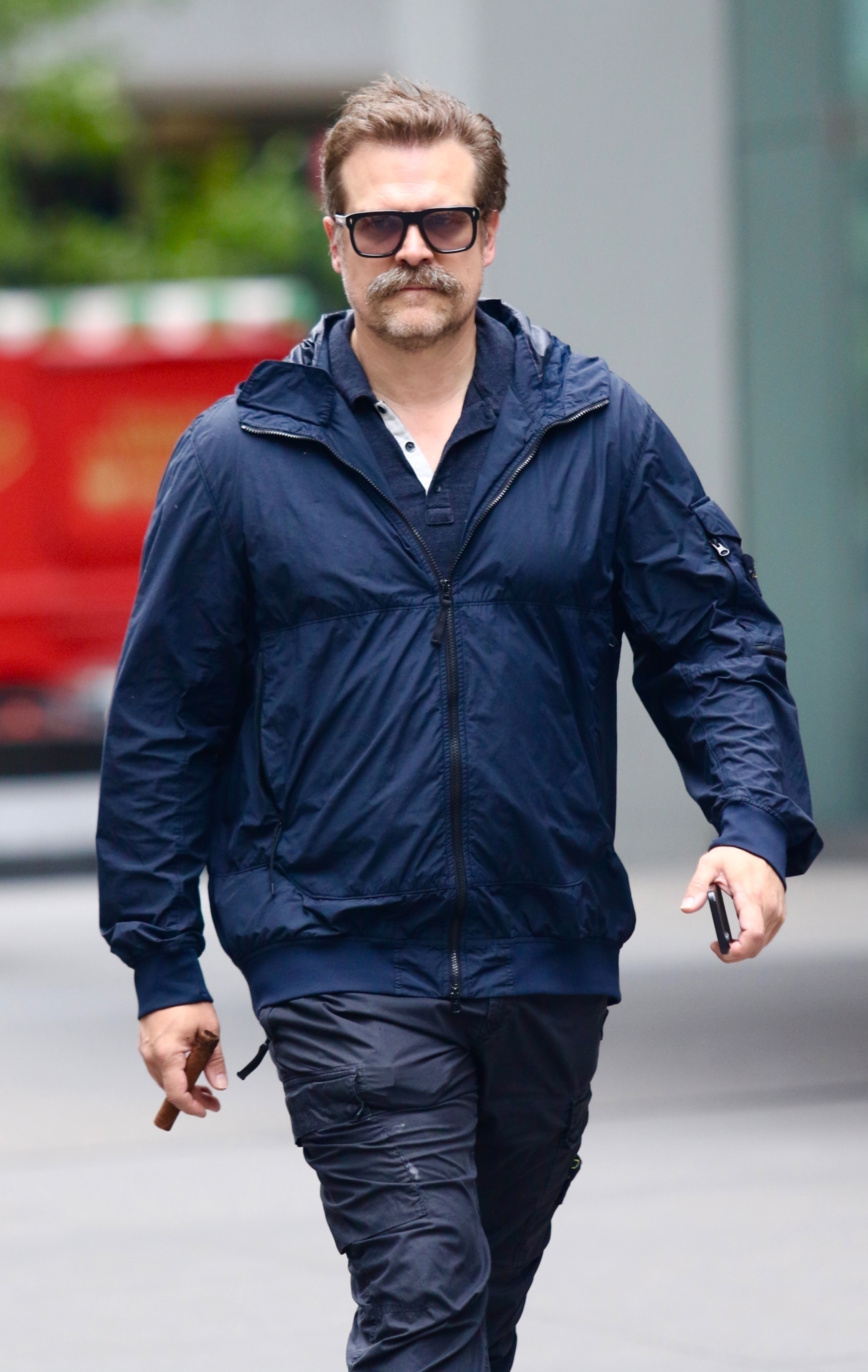 David Harbour strolling in Midtown Manhattan with a mustache and dark shades.