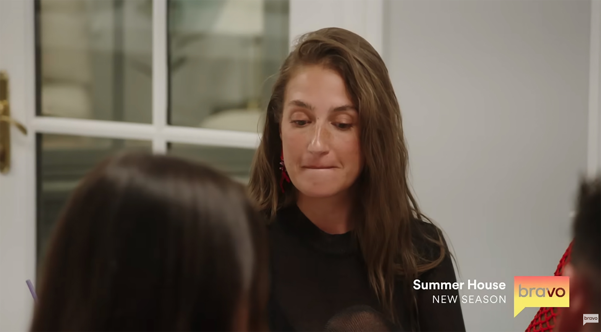 Amanda Batula looking down with her lip bitten, with part of another person's head in the foreground.