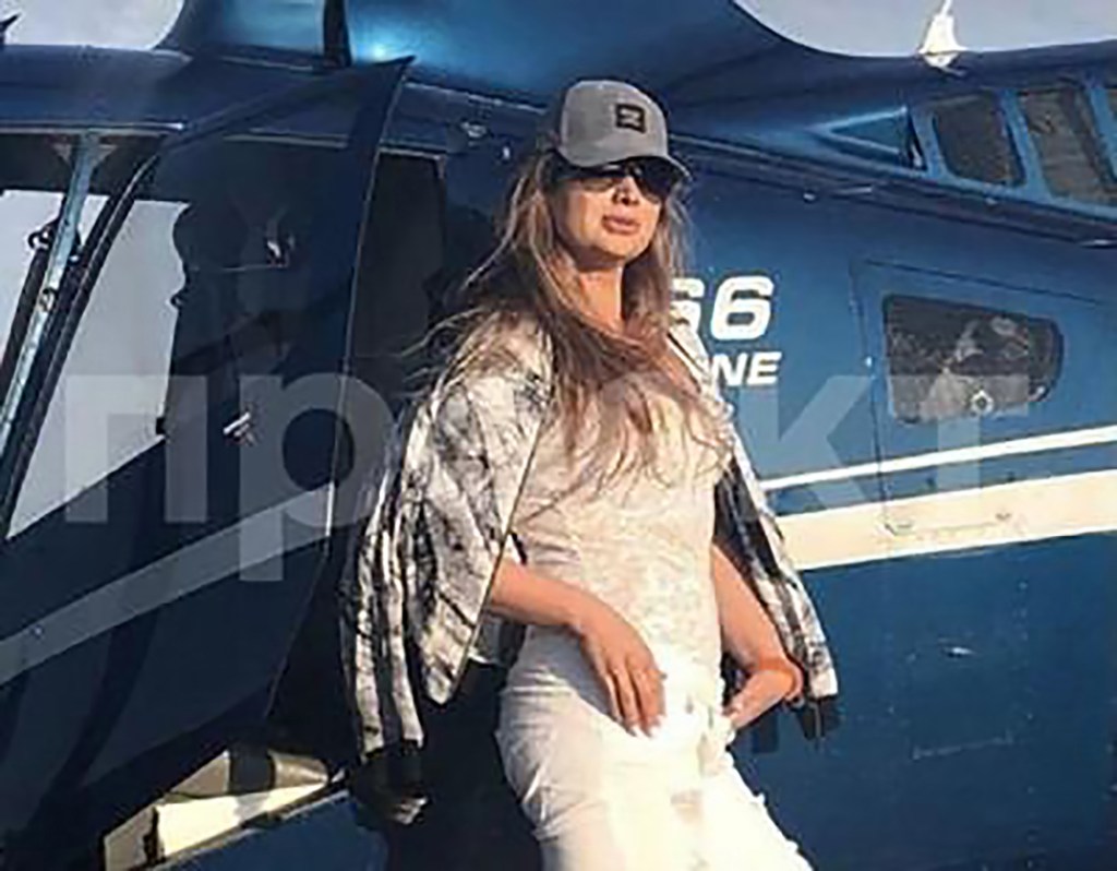 Svetlana Krivonogikh posing in front of a blue helicopter.