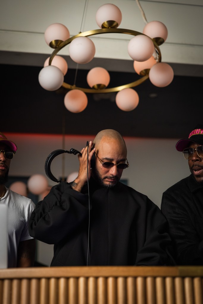 Swizz Beatz at a Miami Art Basel party, holding headphones to his ear.