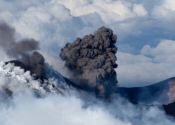 Skier glides down Mount Etna as volcano erupts in the background