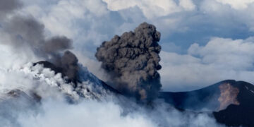 Skier glides down Mount Etna as volcano erupts in the background