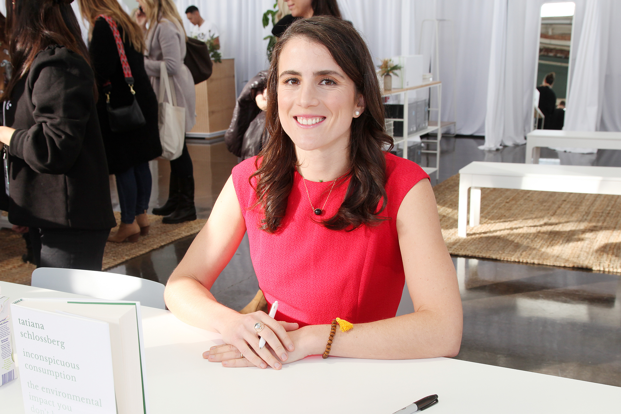 Tatiana Schlossberg smiling while sitting at a table with her book