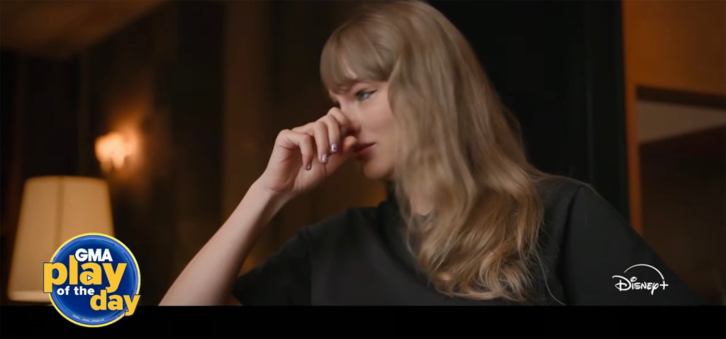 Taylor Swift in a black shirt, wiping away tears.