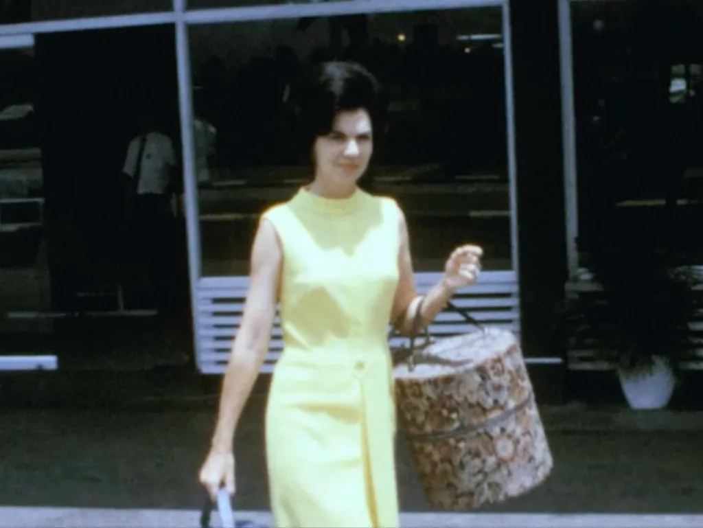 Woman in a yellow dress carrying a round patterned bag.