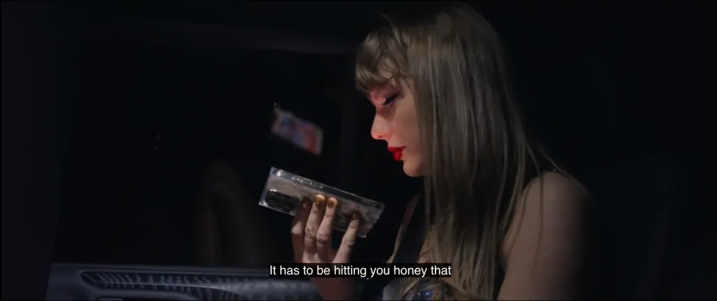 Taylor Swift looking down at her phone with a tear on her cheek.