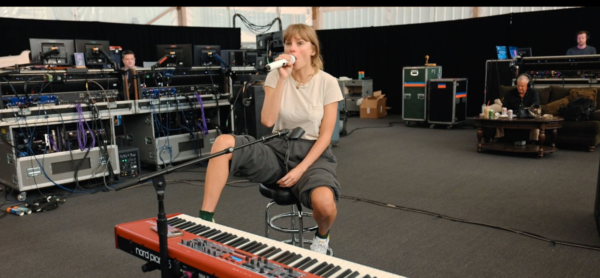 Taylor Swift practicing in a studio with a microphone and a Nord Piano.