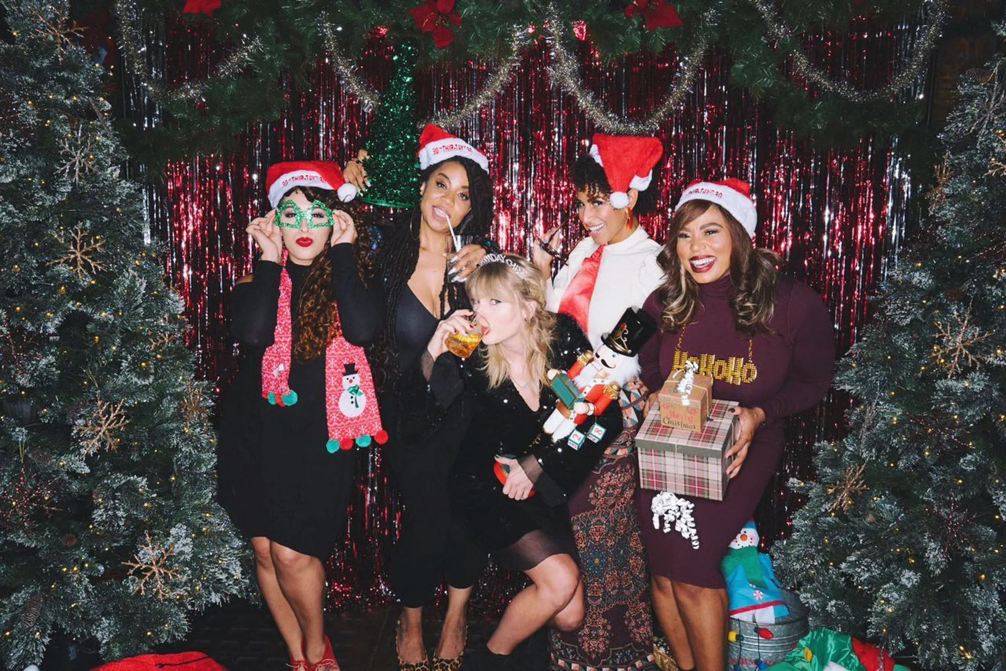 Taylor Swift celebrating Christmas with four friends, all wearing Santa hats, surrounded by holiday decorations.