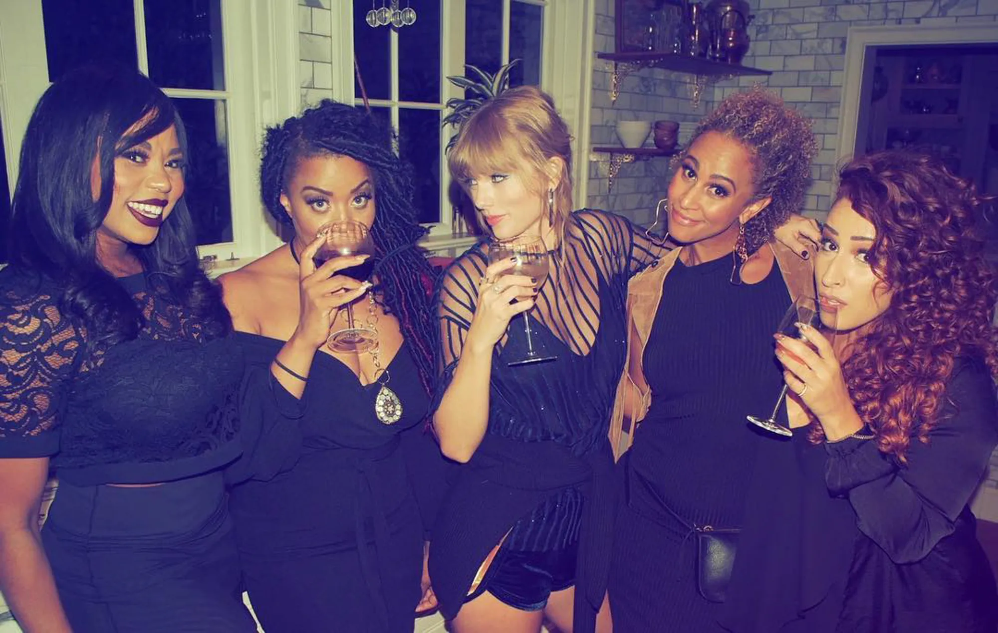 Taylor Swift with a group of friends holding wine glasses.