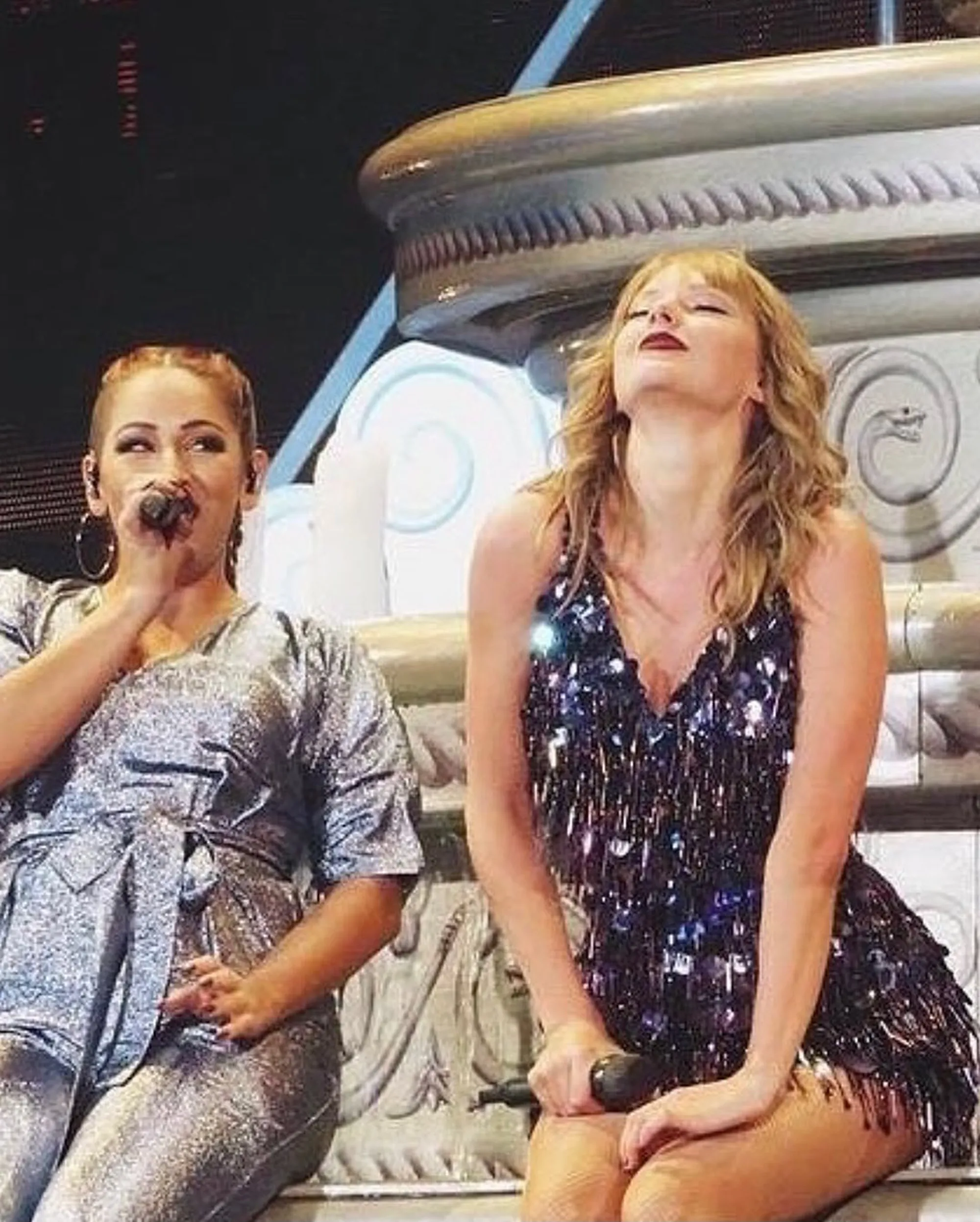 Taylor Swift looking up, eyes closed, beside a dancer on stage.