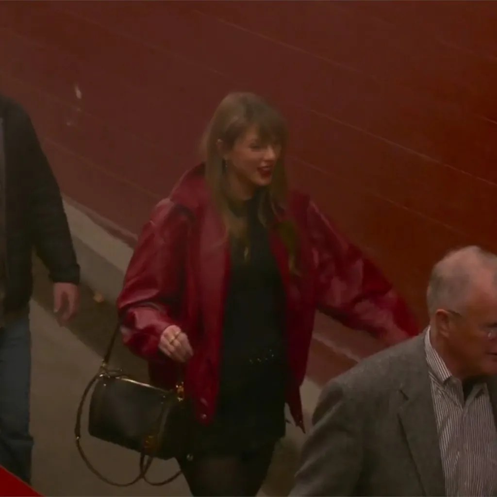 Taylor Swift in a red jacket and black dress at a Chiefs game.