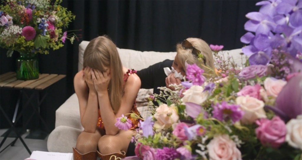 Taylor Swift crying with her face in her hands, while her mother Andrea comforts her from behind.