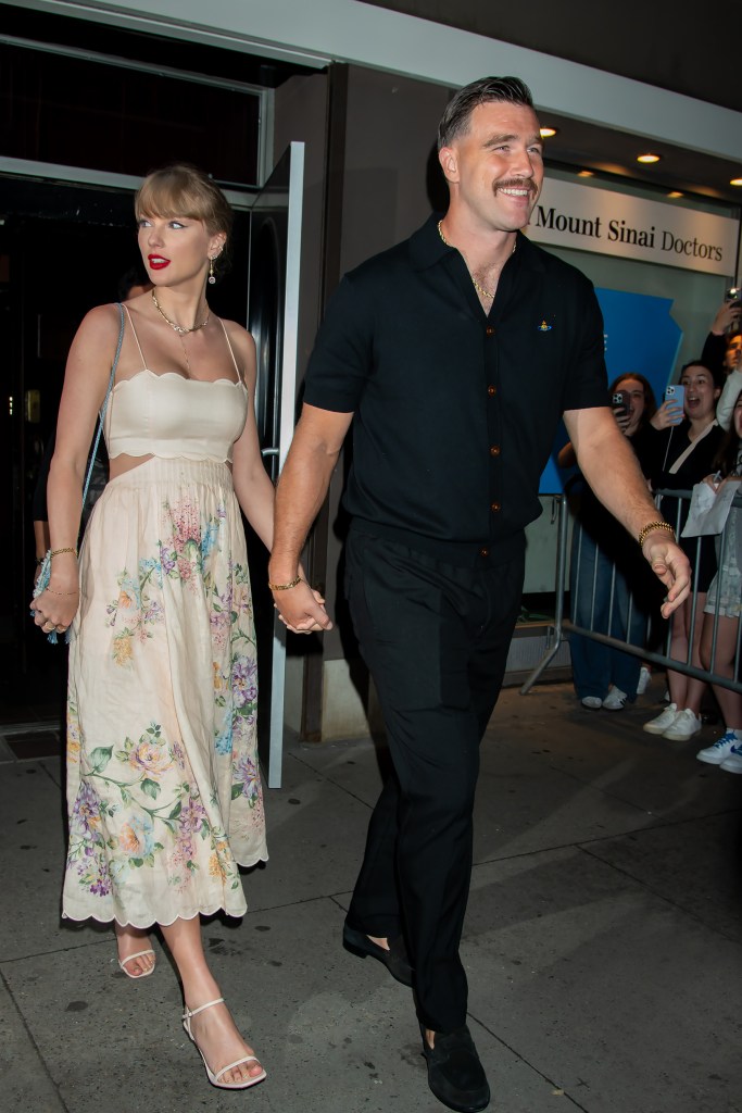 Taylor Swift in a floral print white dress and Travis Kelce in a black short-sleeved shirt holding hands at a wedding.