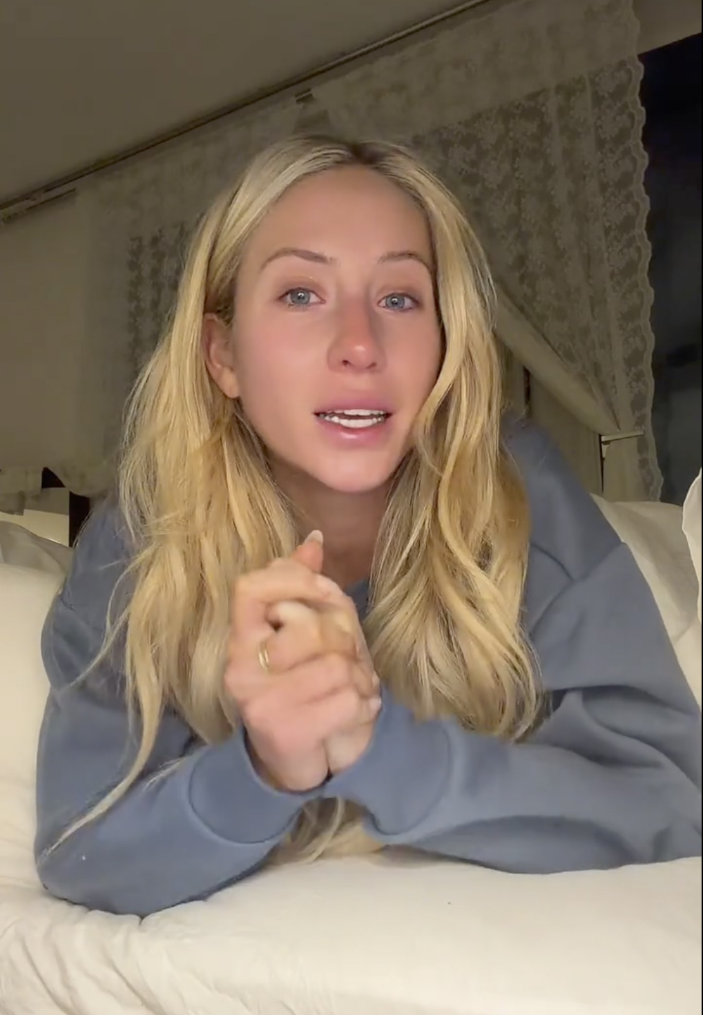 Alix Earle speaking tearfully to the camera, wearing a blue sweatshirt.