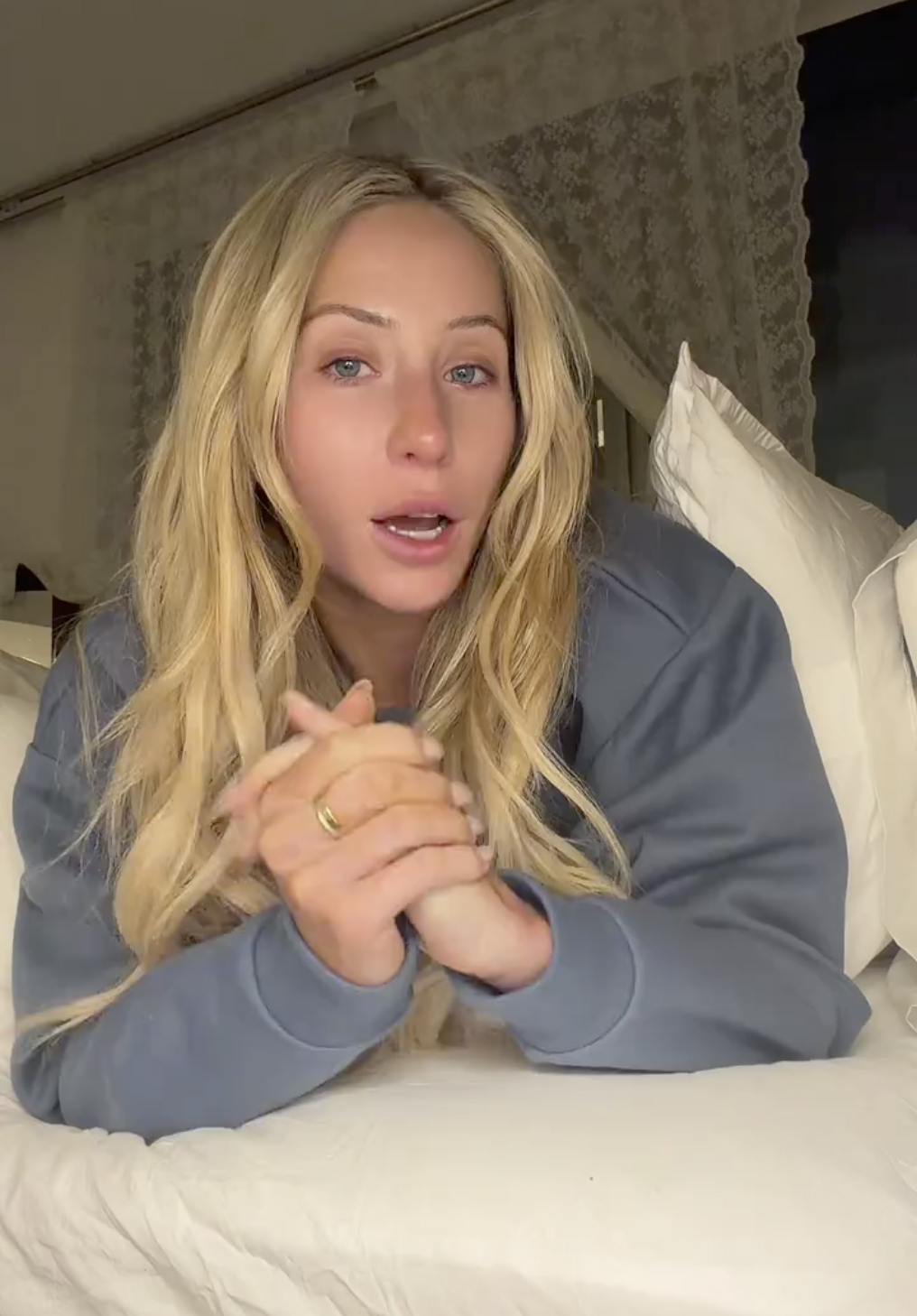 Alix Earle lying on a bed and looking tearful as she speaks.