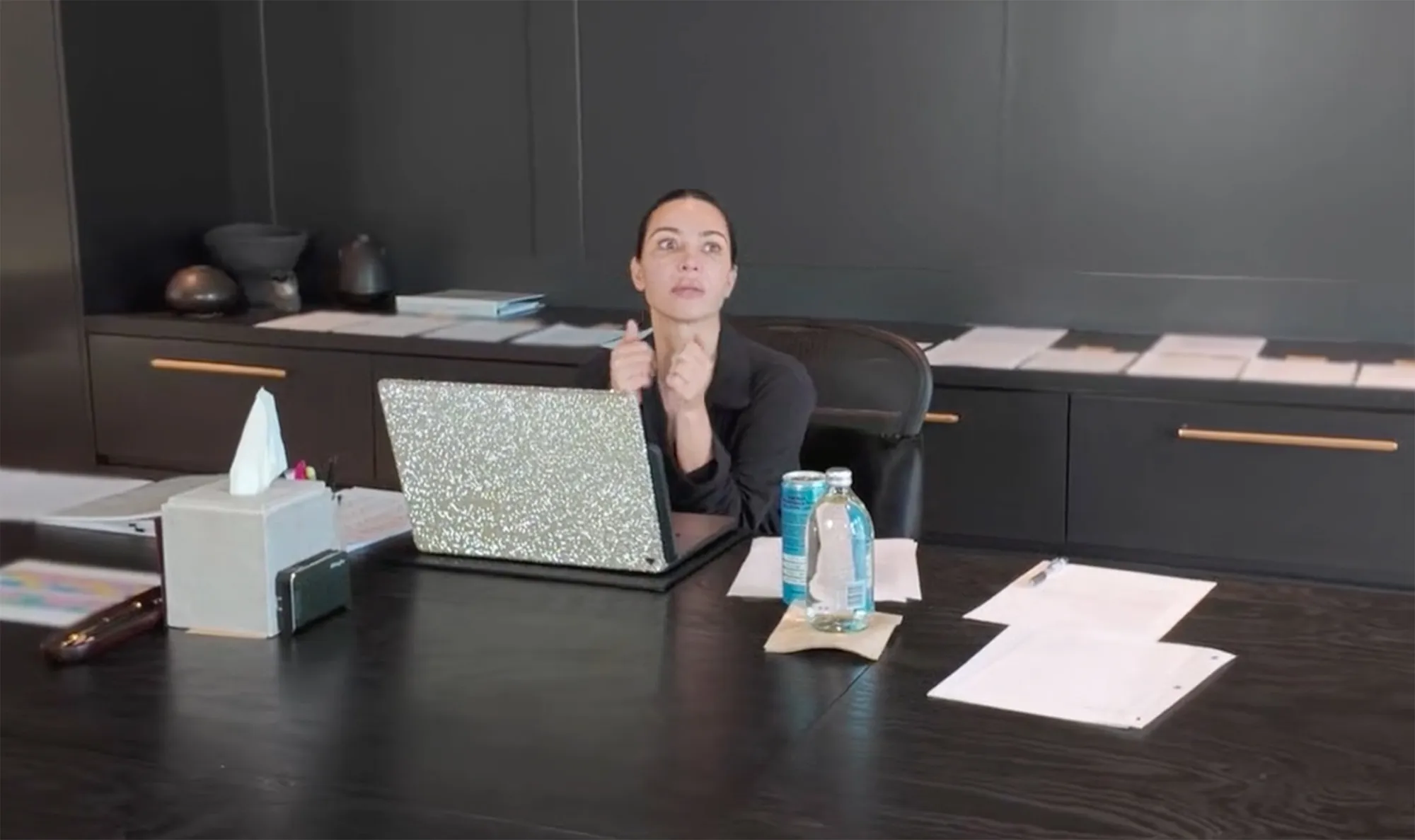 Kim Kardashian sitting at a desk with a laptop, looking distressed.
