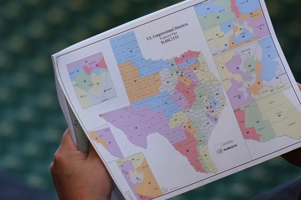 A close-up of a map of Texas, divided into U.S. Congressional Districts by proposed Plan PLANC2333, held by a person.
