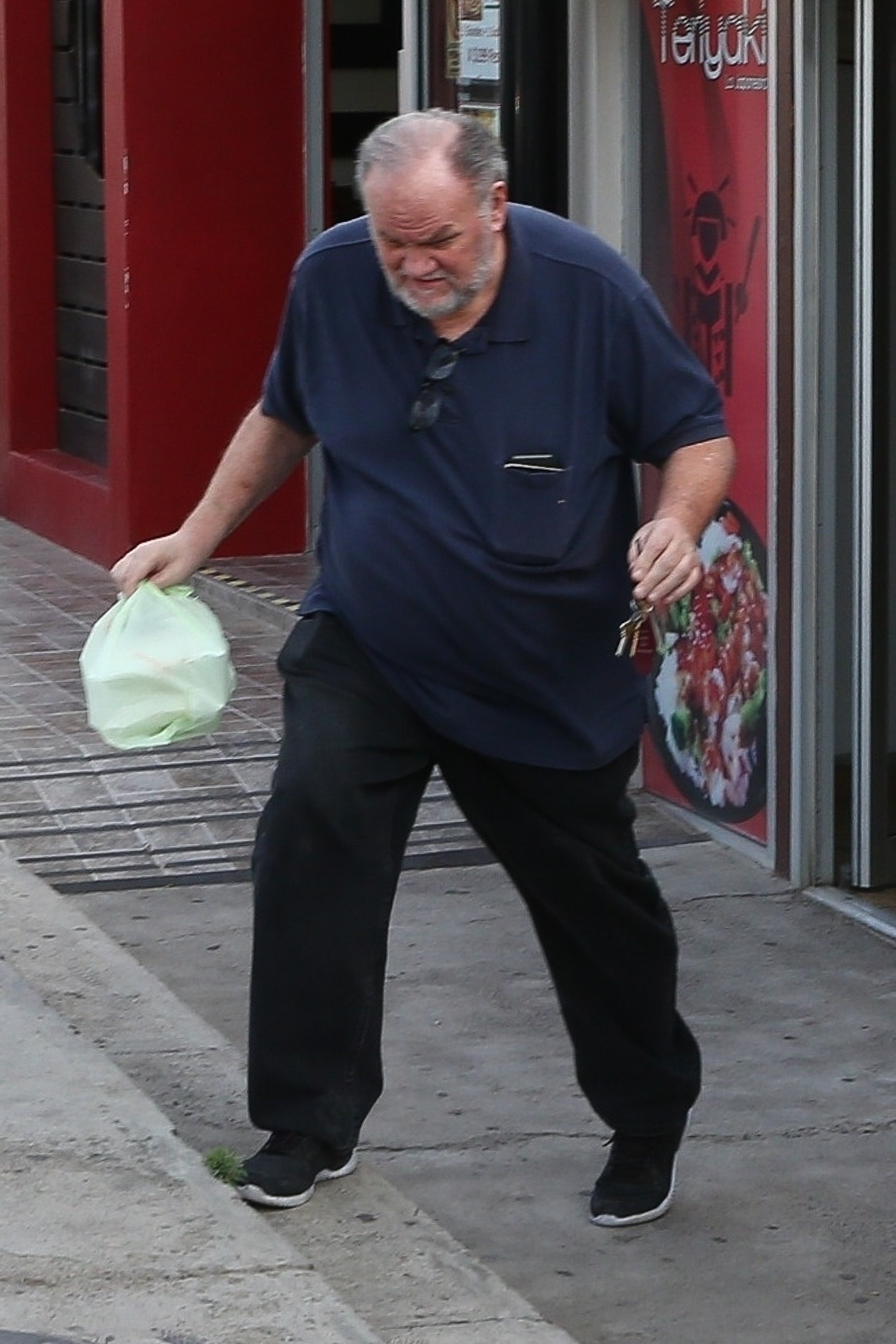 Thomas Markle walking down the street with a bag of teriyaki.