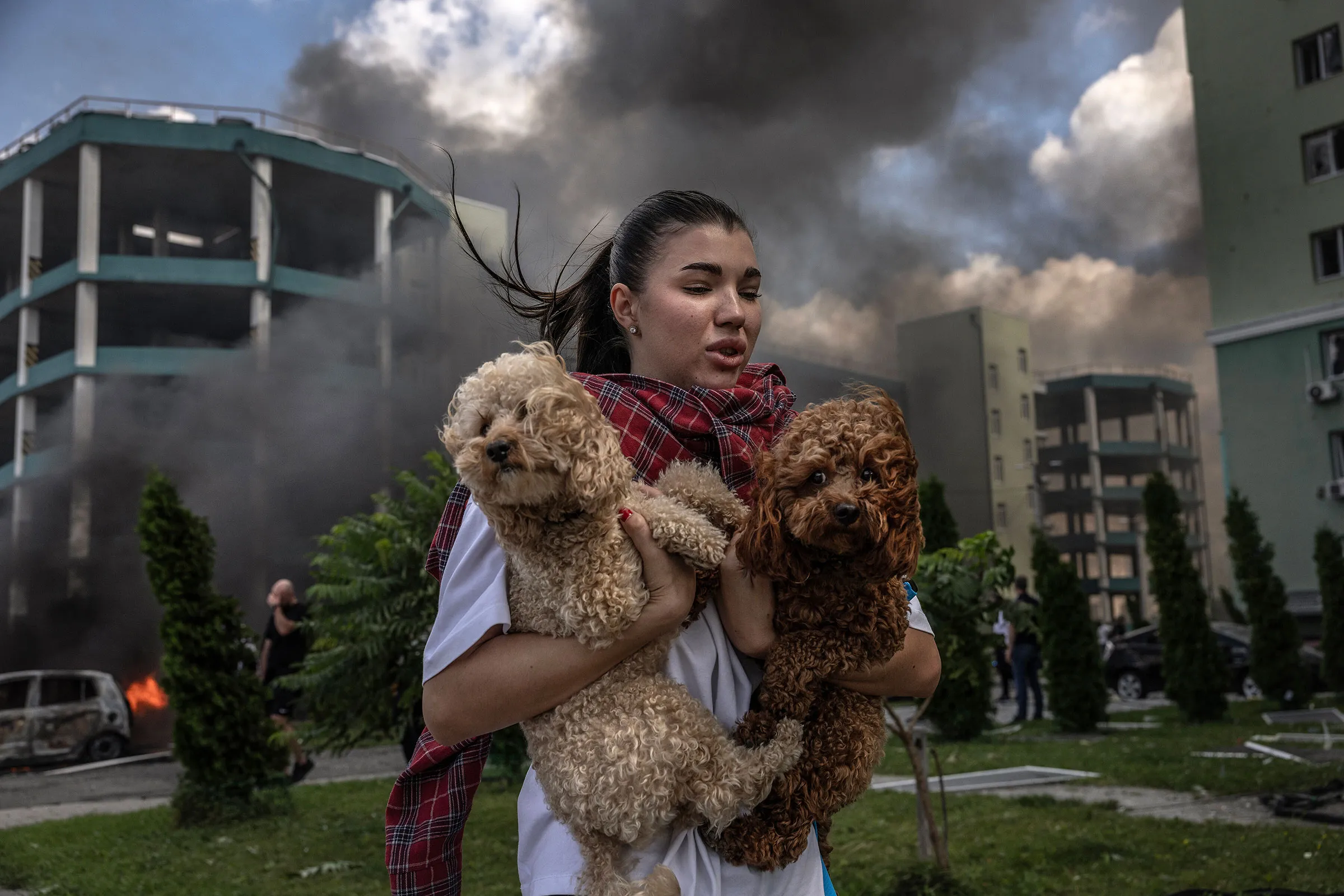 A Ukrainain woman carries pet dogs as she runs from her apartment block after Russian aerial bombs exploded in the area in Kharkiv, Ukraine, July 24, 2025. (David Guttenfelder/The New York Times)