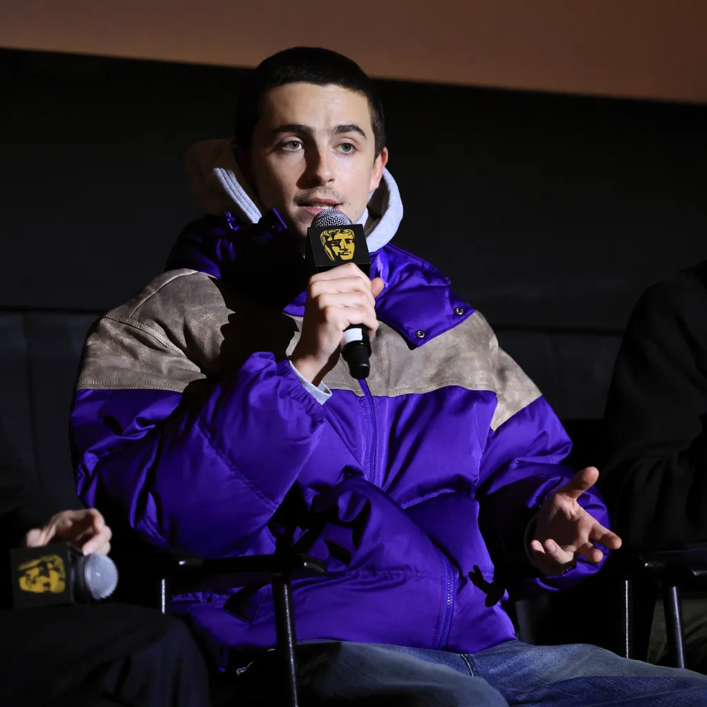 Timothée Chalamet speaks into a BAFTA-branded microphone at the 