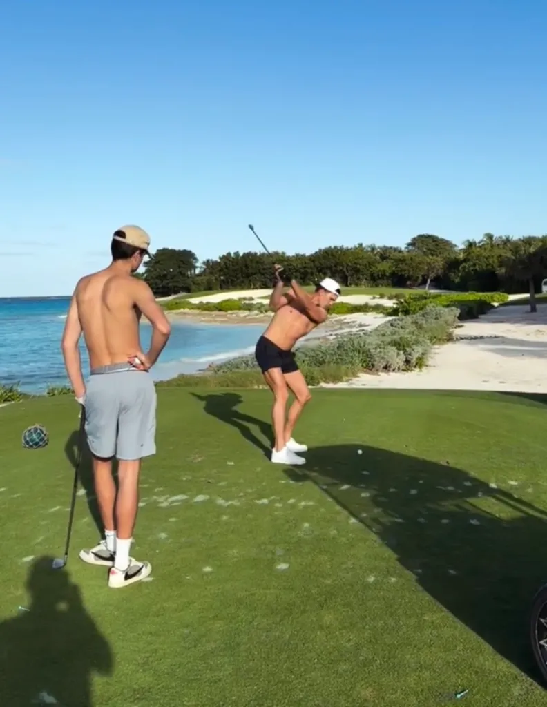 Tom Brady hitting a golf ball shirtless while his son Jack watches.