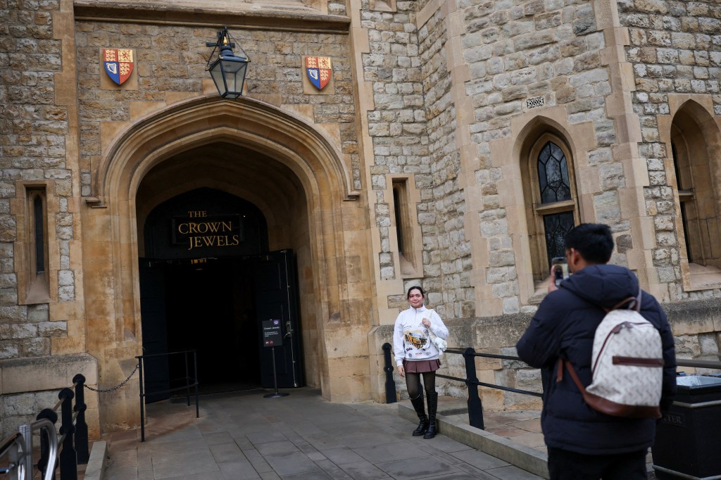 A tourist poses in front of the Crown Jewels entrance at the Tower of London.