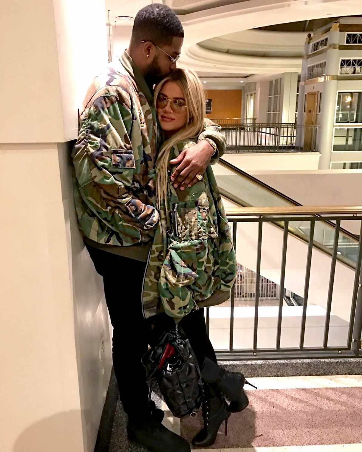 Tristan Thompson and Khloé Kardashian embrace, both wearing camouflage jackets.