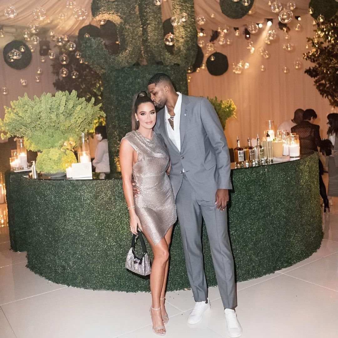 Khloé Kardashian and Tristan Thompson posing together in front of a bar at a party.