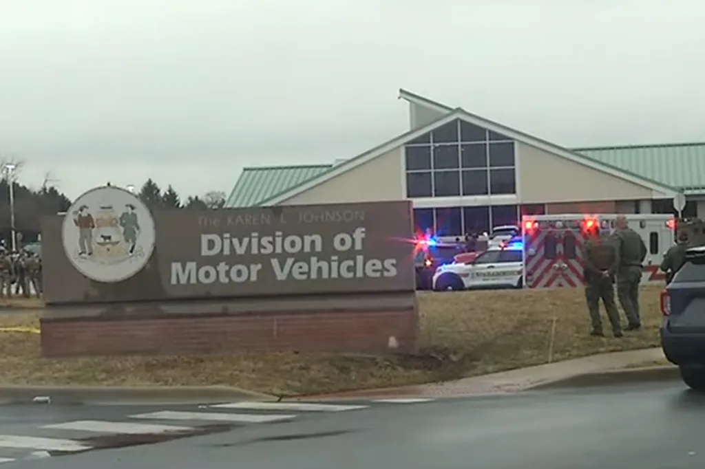 Police and ambulance vehicles with flashing lights outside a building labeled 