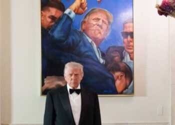 Trump poses with a photo from his assassination attempt after a wave of deadly shootings