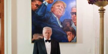 Trump poses with a photo from his assassination attempt after a wave of deadly shootings