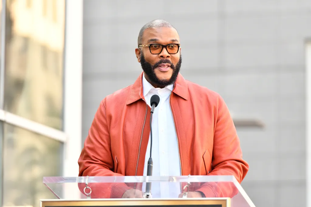 Tyler Perry speaking at a podium.